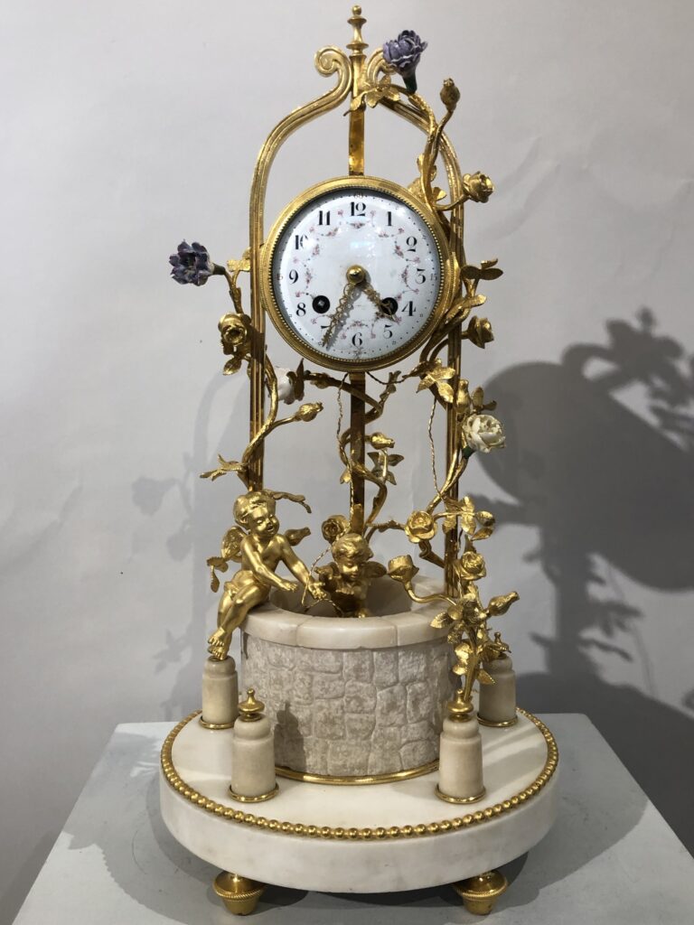 Pendule dorée façon puit, au décor d’anges et de fleurs, fin XIX ème siècle.